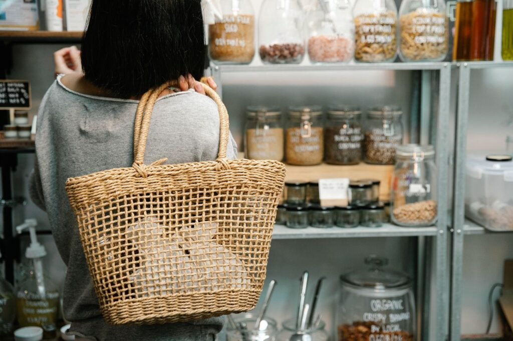 Back view of crop anonymous female with short dark hair choosing goods on shelves in shop